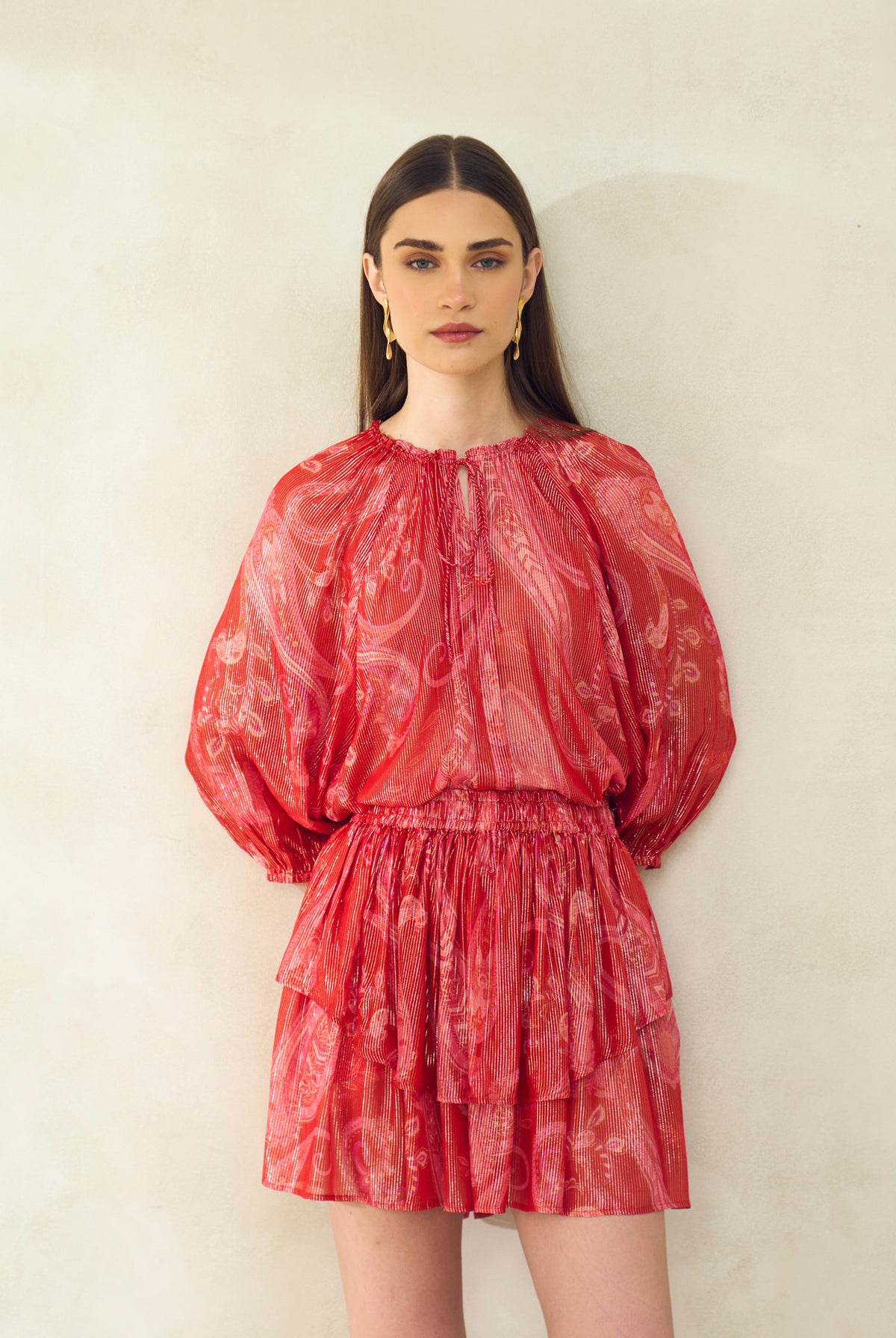 Woman wearing a red patterned dress against a plain background