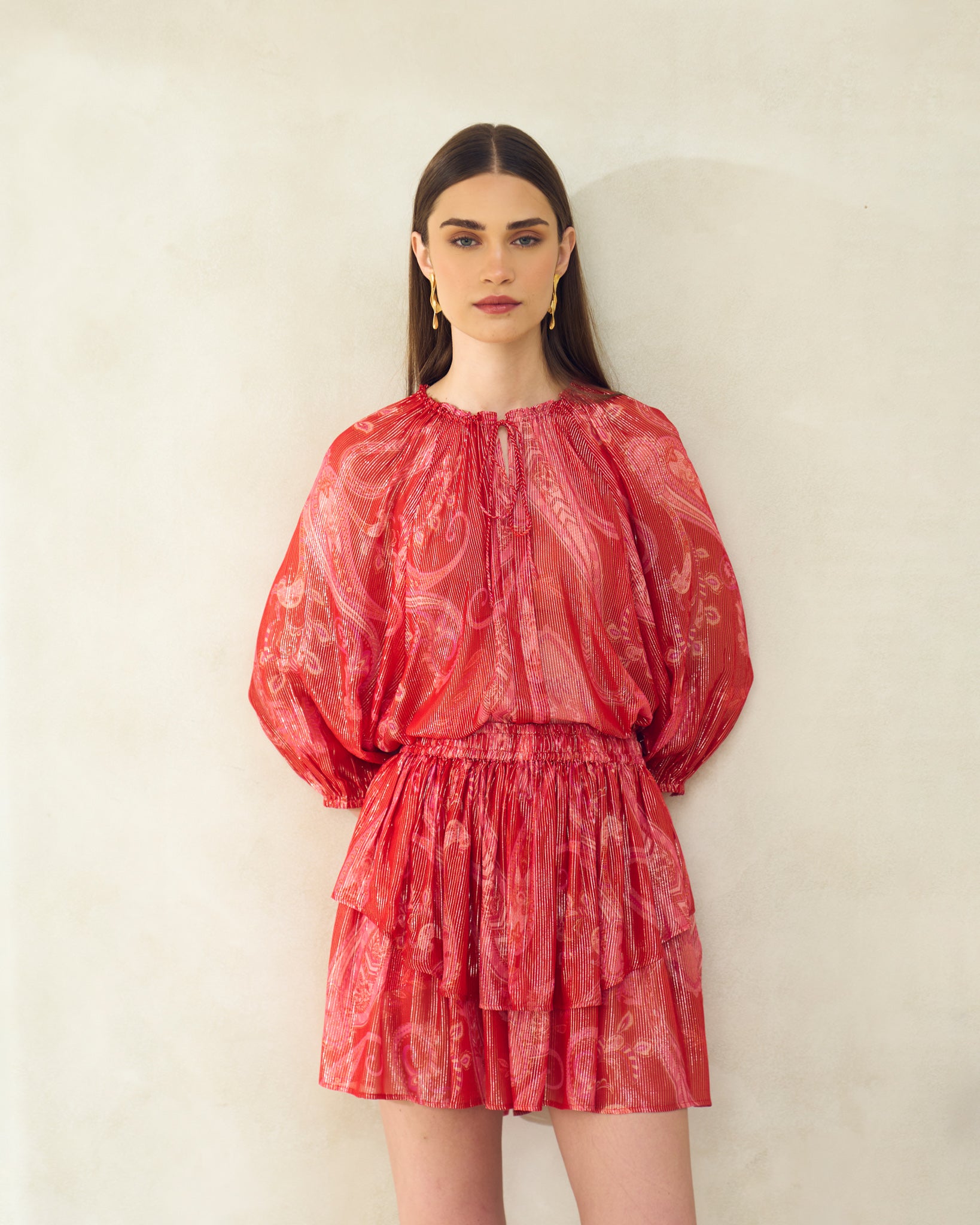 Woman wearing a red patterned dress against a plain background